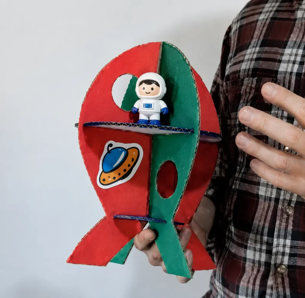 Cohete de cartón reciclado con pisos para jugar con muñecos.